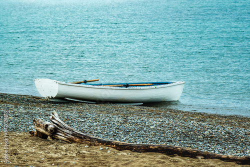 Photography white wooden lifeguard rowboat pulled up at waters edge on kew beach in toronto