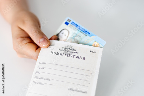 Hand holding Italian Identity Card (ID) and Electoral Card (Tessera Elettorale)