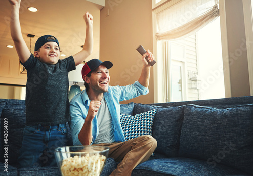 Fototapeta Naklejka Na Ścianę i Meble -  Television, kid and man with success on sofa for network, streaming and watching sports together. Son, dad and popcorn with tv remote in fist for celebration, bonding and live broadcast of match