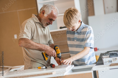 A grandfather teaches his grandson how to fix furniture in his carpenter workshop.