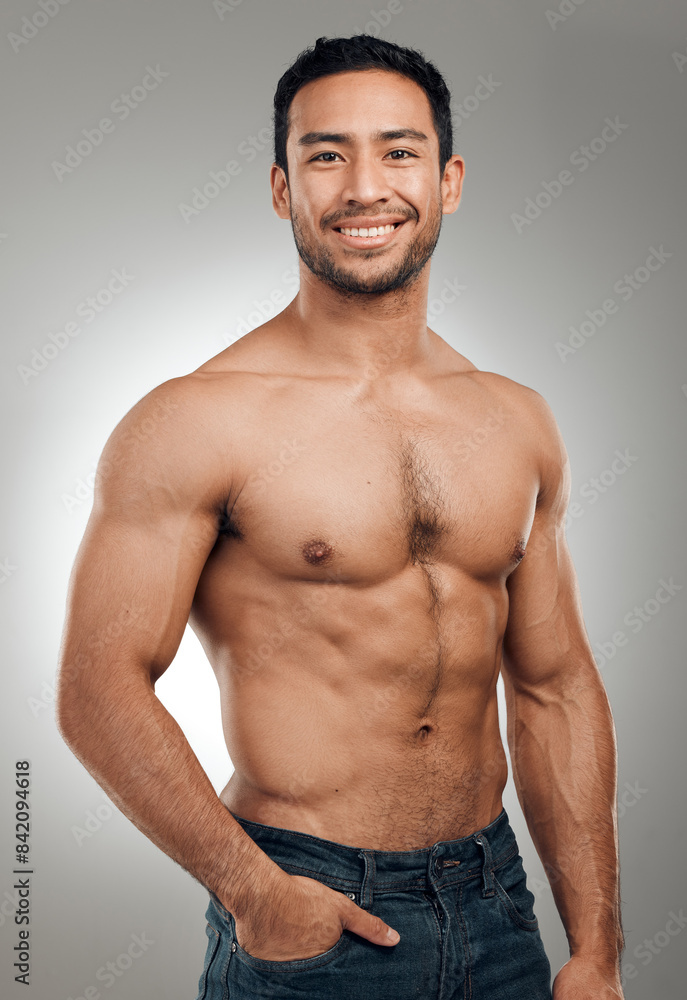 Fototapeta premium Man, portrait and happy in studio with abs or muscles, shirtless and grey background with model or bodybuilder. Jeans, strong chest and Asian male person on backdrop, confidence with six pack