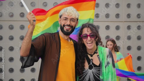 Gay young man and lesbian woman celebrating the lgbt pride with their friends, waving the rainbow flag and havin fun together. Real diverse people claim for their sexual rights at equality party photo