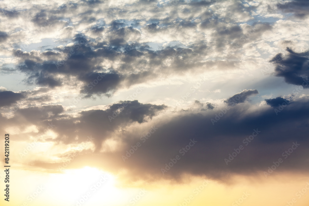 Serene sunset sky with fluffy clouds and a radiant sun Serene sunset sky with fluffy clouds and a radiant sun
