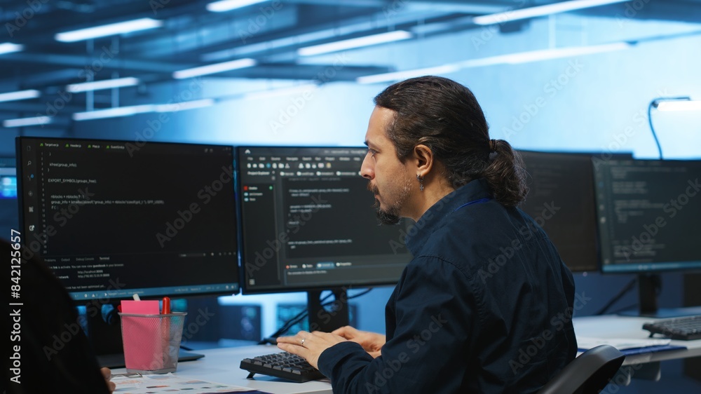 Knowledgeable engineer upgrading equipment in data center, zoom in shot. Specialist at PC desk in high tech establishment overseeing server rows, typing on keyboard, close up shot