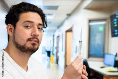 Man holding two syringes in the room of the hospital with copy space