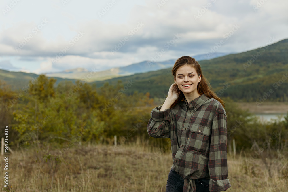Woman embracing nature A fashionable traveler in plaid shirt posing in a picturesque mountain field Woman embracing nature A fashionable traveler in plaid shirt posing in a picturesque mountain field