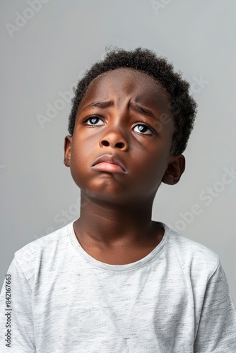 Emotional African-American boy on light grey background