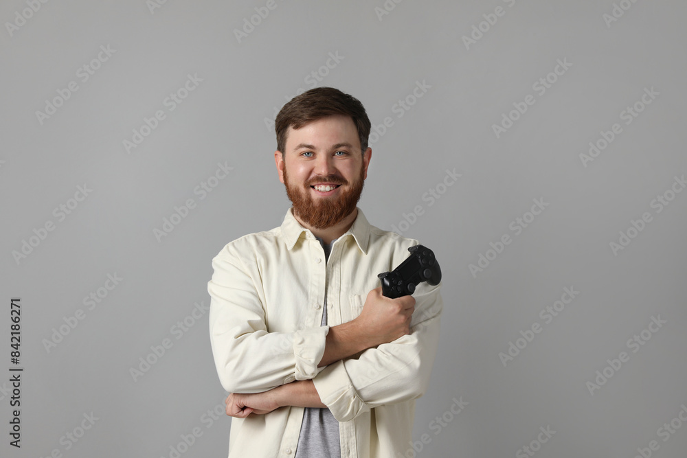 Smiling man with game controller on grey background Smiling man with game controller on grey background