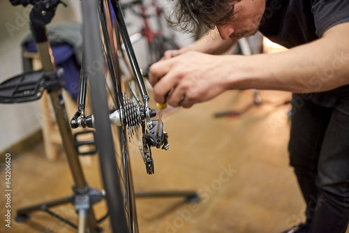 Repairman working: hispanic man concentrated adjusting a bicycle derailleur in his repair shop. Real people at work.
