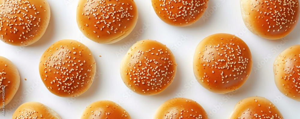 Fresh sesame seed burger buns arranged on white background, top view. Food and bakery concept Fresh sesame seed burger buns arranged on white background, top view. Food and bakery concept