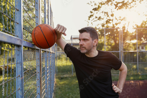 Bearded man resting on the fence after intense basketball practice 