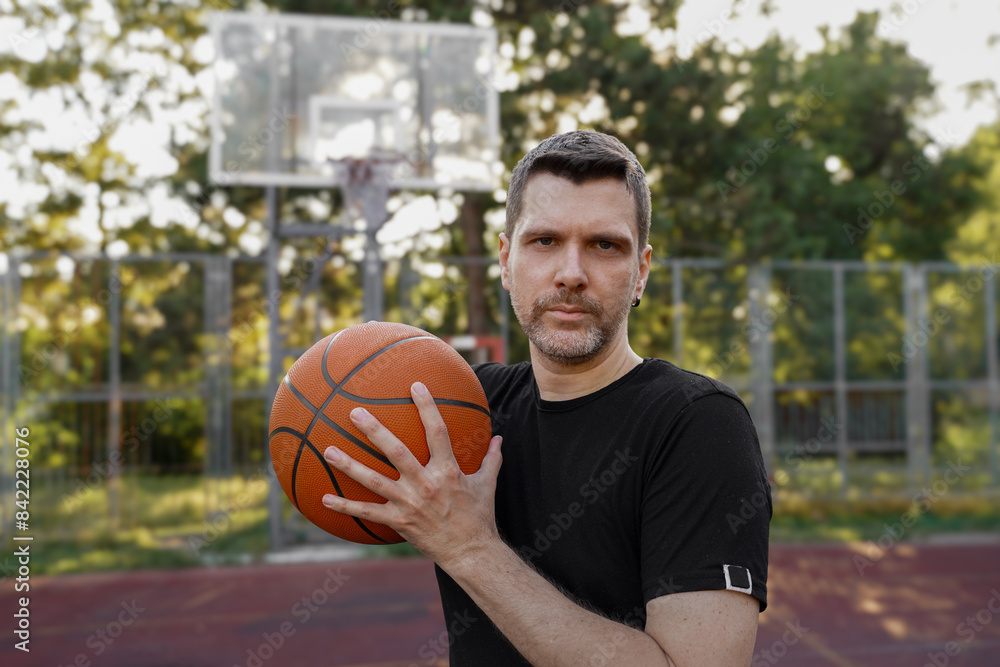 Man with basketball ball on court posing, looking at camera Man with basketball ball on court posing, looking at camera