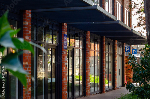 фотографія A street-level view of a modern building with a brick facade, large glass windows, and several storefronts or entrances
