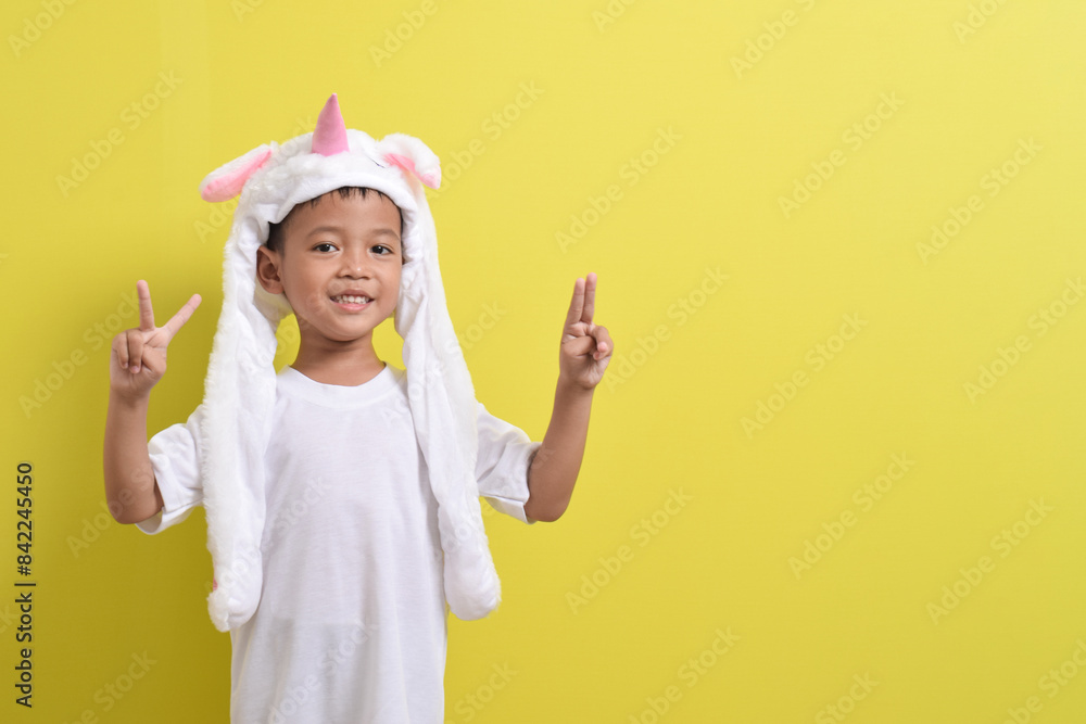 Asian little boy posing wearing cute character hat on yellow background. Portrait of a cute Asian boy Asian little boy posing wearing cute character hat on yellow background. Portrait of a cute Asian boy