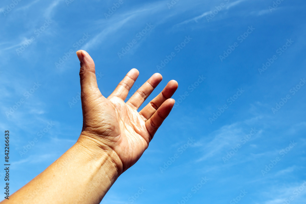 One left hand reaching up to the bright blue sky in hope. One left hand reaching up to the bright blue sky in hope.
