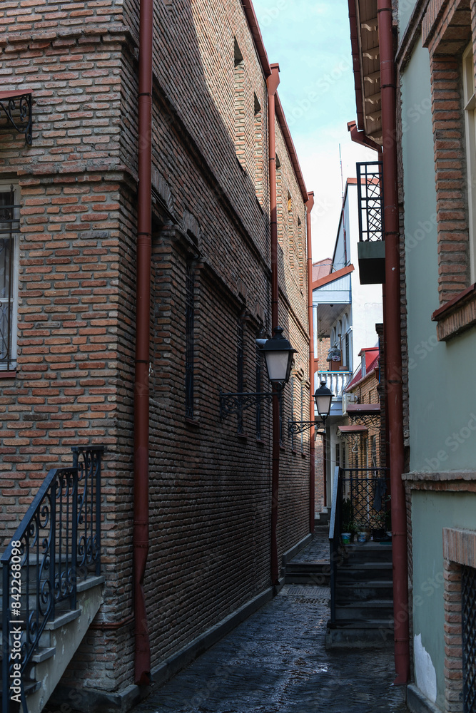 Fototapeta premium narrow street with lanterns between houses in the center of old Tbilisi