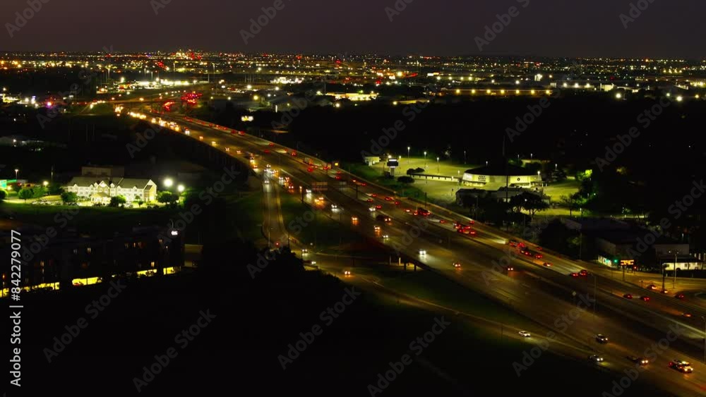 Aerial view of vehicles on a busy highway at night in the USA, with vibrant lights in the outskirts of a big american city Aerial view of vehicles on a busy highway at night in the USA, with vibrant lights in the outskirts of a big american city