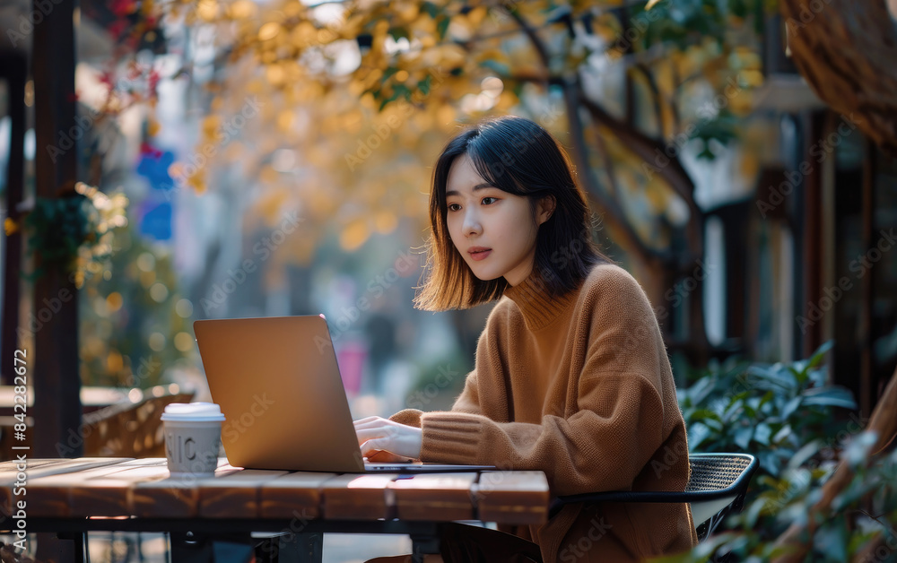 Freelancer woman works typing on laptop and looking at the monitor wearing brown knitted cardigan. Freelancer, businesswoman Freelancer woman works typing on laptop and looking at the monitor wearing brown knitted cardigan. Freelancer, businesswoman