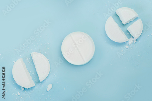 round tablet was divided equally. White broken pills lie on a blue background. photo