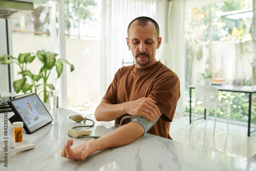 Man suffering from hypertension measuring blood pressure at home Man suffering from hypertension measuring blood pressure at home