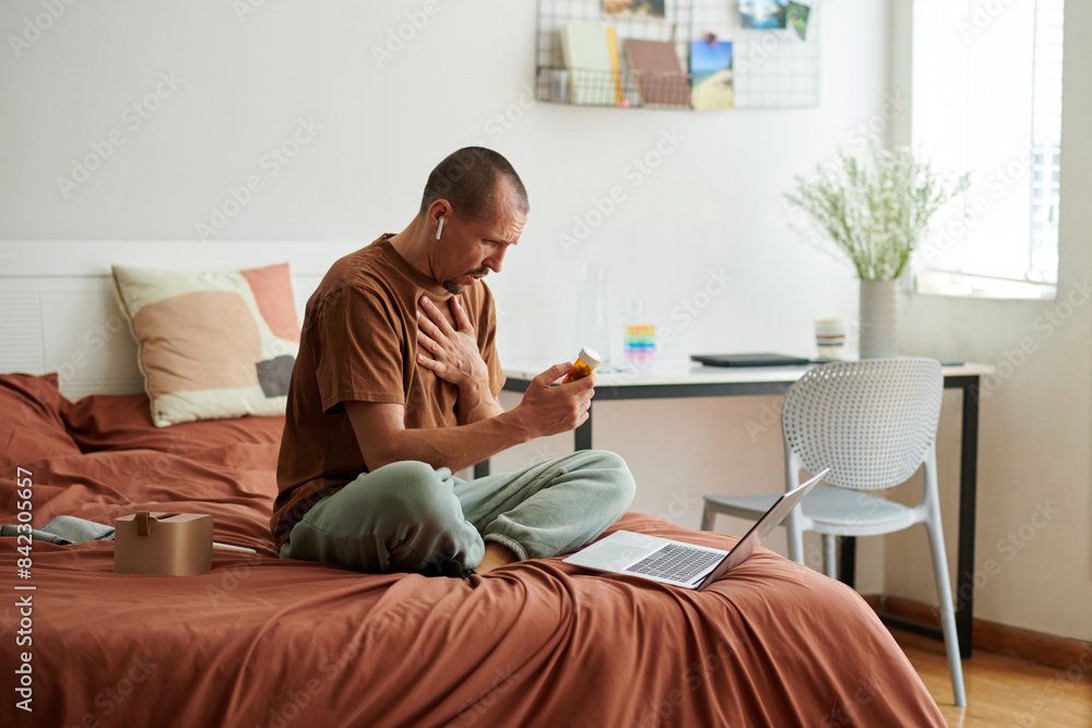 Man suffering from chest tightness video calling doctor and showing medicine he takes