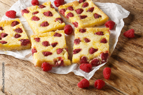 German open pie Raspberry Custard Kuchen or himbeerkuchen closeup on the paper on the wooden table. Horizontal photo