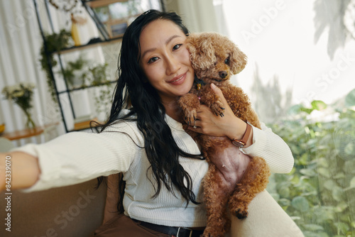 Smiling young woman taking selfie with her small dog