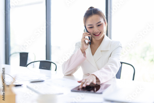 Asian Businesswoman Using laptop computer and working at office with calculator document on desk, doing planning analyzing the financial report, business plan investment, finance analysis concept.
