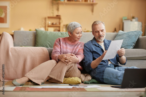 Картината върху платно Full length portrait of modern senior couple sorting financial documents while s