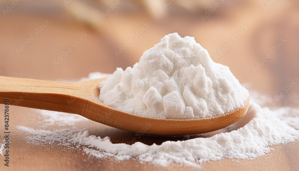 Pile of white wheat flour in wooden spoon Pile of white wheat flour in wooden spoon
