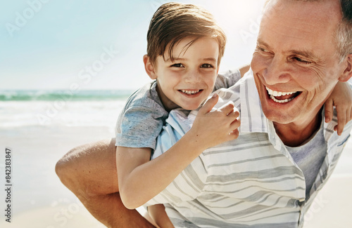 Foto Happy, piggyback and grandfather with child at beach for summer, fun and bonding on vacation in nature