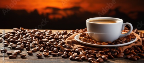 cup of coffee and coffee beans on wooden table on darker background, top view