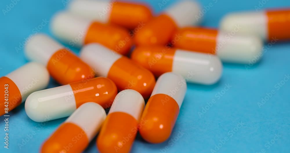 white-orange pills with a crystalline drug inside, medical drugs in close-up on a blue background white-orange pills with a crystalline drug inside, medical drugs in close-up on a blue background