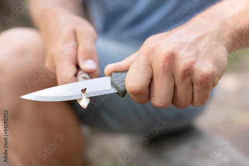 young man with a knife cut a wooden stick