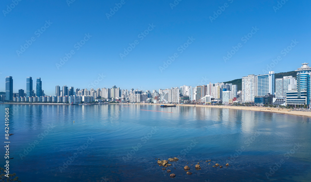 Obraz premium Gwangalli beach skyline with modern buildings reflected in the water on a sunny day