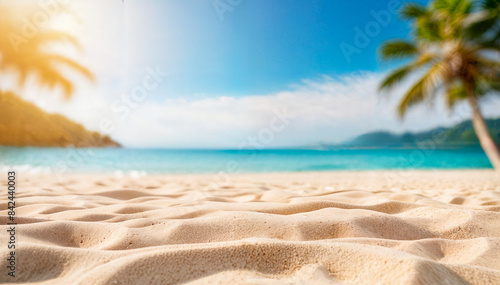 A sandy beach with a blurred tropical landscape in the background, including a clear blue sky and ocean photo