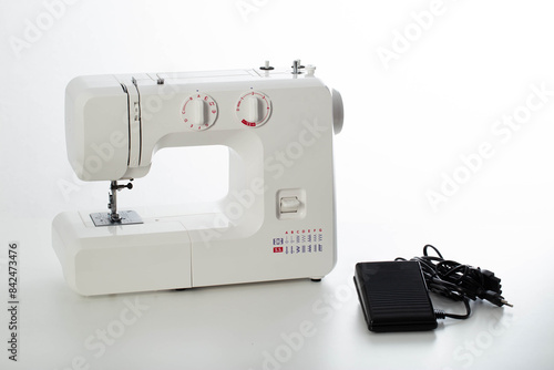 Fotografia Automatic modern sewing machine with overlock and black pedal on a white background, isolate