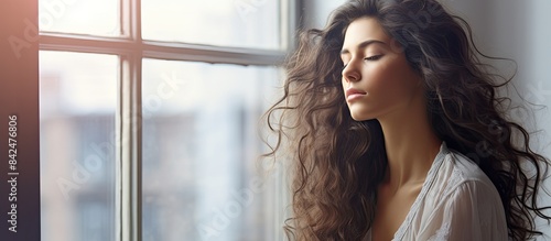 Latin woman relaxing by a window with closed eyes, enjoying the music of raindrops and the fresh air after a storm, with a serene side shot. Copy space image available. Free Download Latin woman relaxing by a window with closed eyes, enjoying the music of raindrops and the fresh air after a storm, with a serene side shot. Copy space image available. - GFXLoad