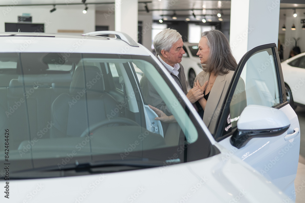 An elderly Caucasian couple chooses a new car at a car dealership. An elderly Caucasian couple chooses a new car at a car dealership.