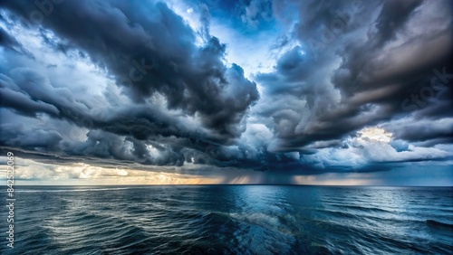 A vast expanse of stormy grey clouds hangs low over a choppy  dark blue sea  creating a dramatic and moody atmosphere  clouds  sea  ocean  storm  dramatic  moody  sky  water  nature  weather