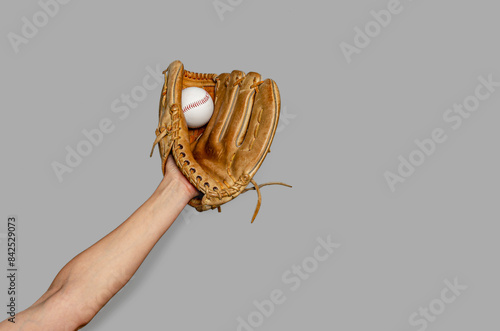 Female baseball gloved hand catches ball. Gray background. Active sport, championship, victory.