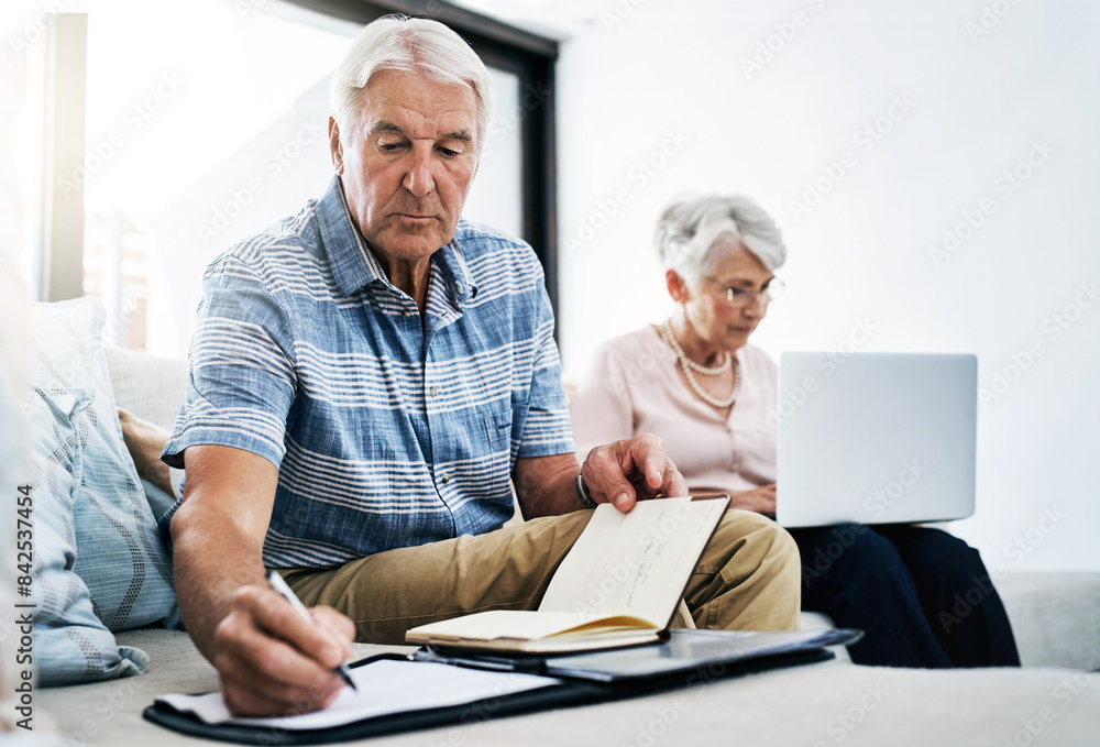 Senior couple, laptop and serious with writing on document in sofa for retirement or shopping list for household. People, planning and budgeting at home for savings, insurance and asset management Senior couple, laptop and serious with writing on document in sofa for retirement or shopping list for household. People, planning and budgeting at home for savings, insurance and asset management