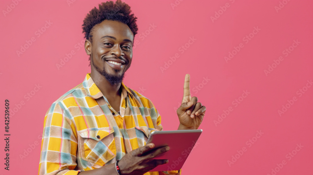 Fototapeta premium A man with a plaid shirt is smiling, holding a tablet, and making a gesture upwards