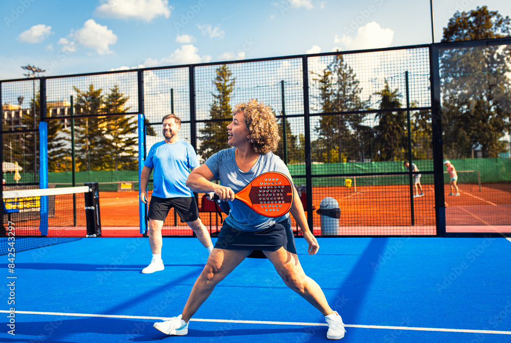Obraz premium Mixed adult couple playing padel on outdoor court.