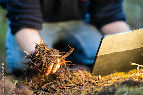 scientist researcher studying soil and forest health effects from climate change. university student research on bush soil structure and biology diversity. holding a soil sample in hand taking photos photo