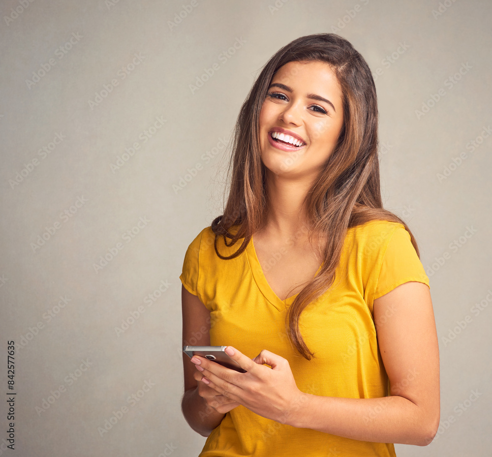 Woman, happy and portrait with smartphone in studio background for social media, networking and online dating. Female person, smile and satisfied with good news, streaming platform and entertainment Woman, happy and portrait with smartphone in studio background for social media, networking and online dating. Female person, smile and satisfied with good news, streaming platform and entertainment