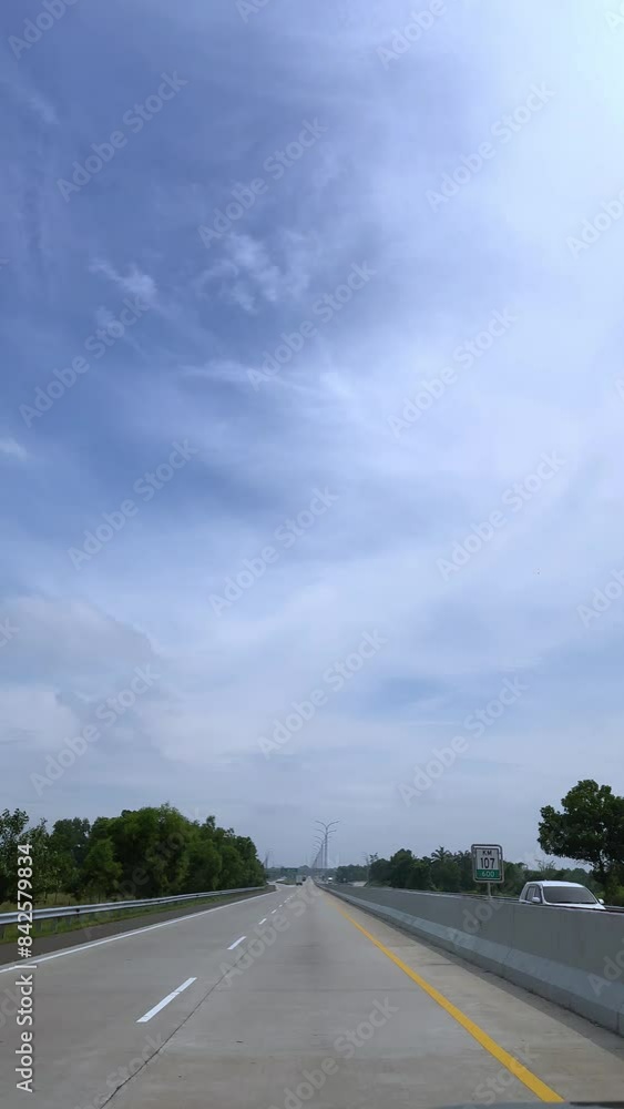 A highway with a blue sky and trees in the background. There are several cars and a bus on the road A highway with a blue sky and trees in the background. There are several cars and a bus on the road