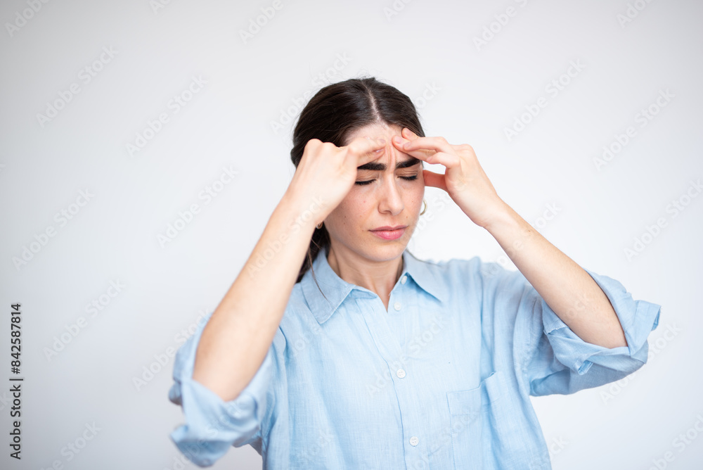 Young woman suffering from a strong headache is touching her temples with fingers Young woman suffering from a strong headache is touching her temples with fingers