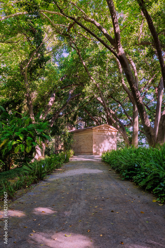 Pathway leading to a small building in a leafy green park © MiguelAngel