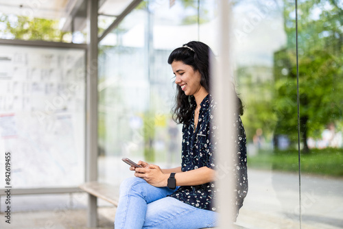 Young woman using smart phone at the bus stop in the city  © pikselstock